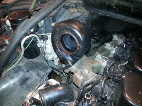 1994 Ford Bronco - A close-up view of a turbocharger installed on an engine, likely within a 1994 Ford Bronco. The turbocharger is black and appears to be a r…