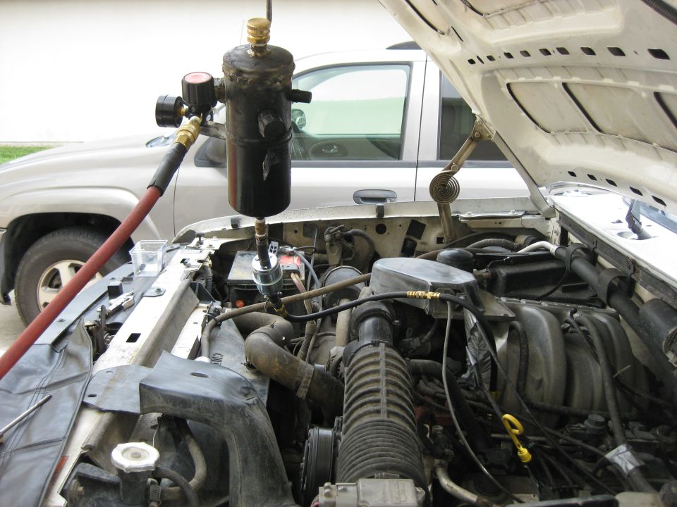 1994 Ford Bronco engine bay with custom vacuum accumulator tank and red hose.
