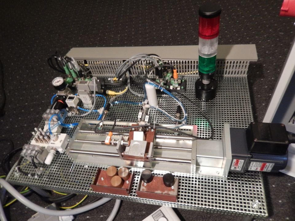 Industrial automation setup with pneumatic valves, sensors, motor, and stack light.
