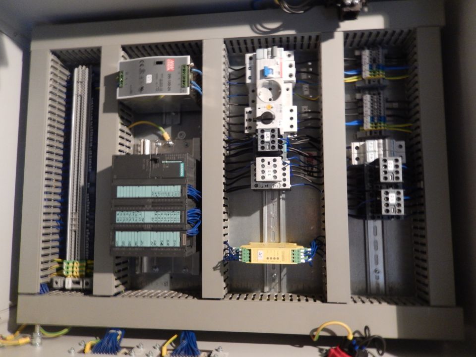Electrical control panel with circuit breakers, relays, and wiring inside a gray cabinet.