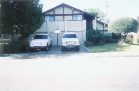 1988 Ford Bronco - Two SUVs are parked in a driveway in front of a house with a basketball hoop.