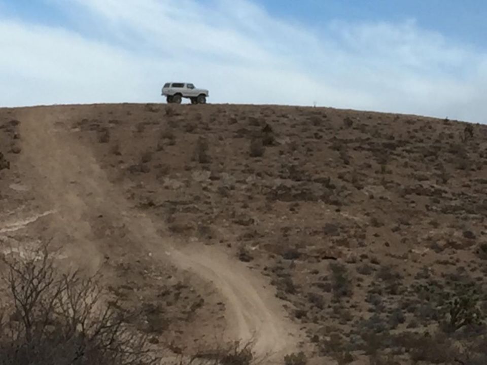 Off-road vehicle on a dirt hill under a blue sky