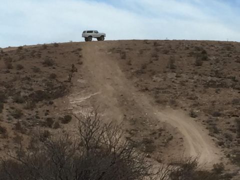 1979 Ford Bronco - A lone SUV travels up a dusty trail under a wide, open sky.
