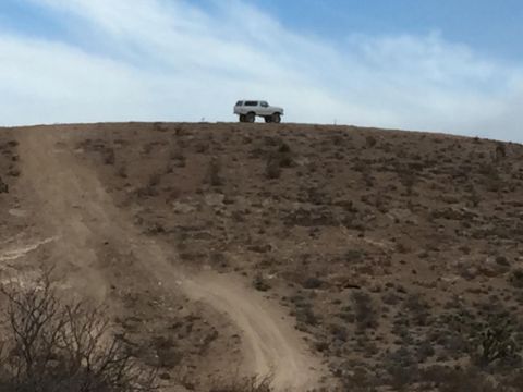 1979 Ford Bronco - A 1979 Ford Bronco is parked on a dirt mound with a clear sky above.