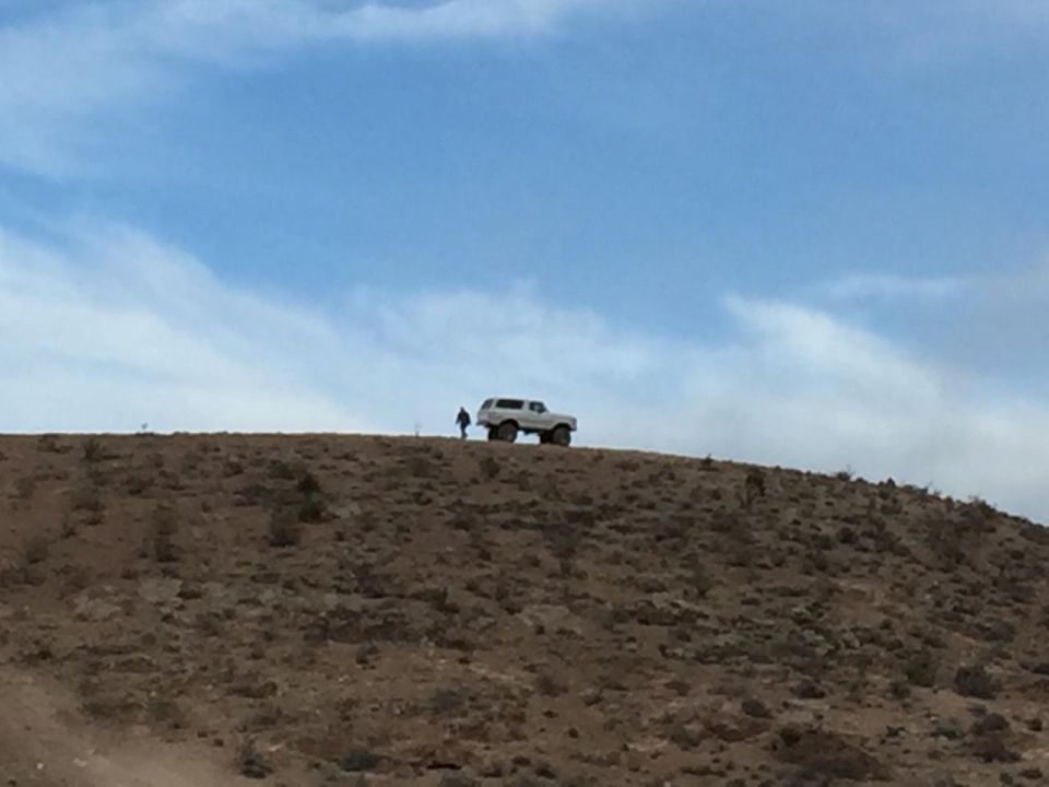 SUV silhouetted on a dusty hill under a blue sky