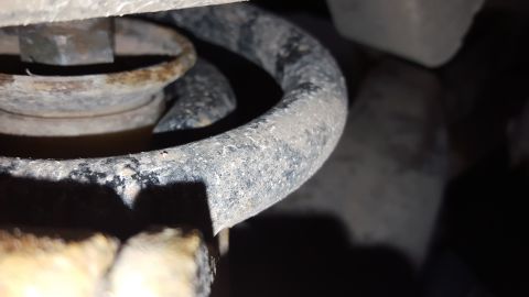 1995 Ford Bronco - A close-up view of a vehicle's suspension spring and bolt, showing signs of rust and wear.