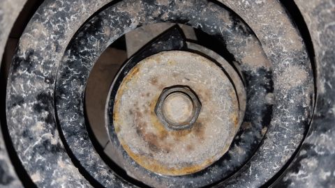 1995 Ford Bronco - This image shows a close-up view of a rusty bolt and nut securing a suspension component on a vehicle.