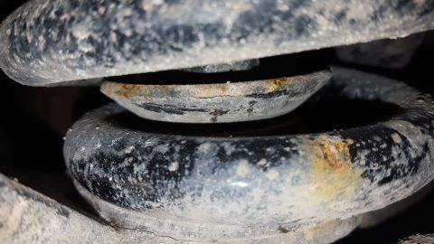 1995 Ford Bronco - A close-up view of a vehicle's suspension spring and mount, showing signs of rust and wear.
