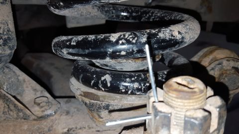 1995 Ford Bronco - Close-up view of a vehicle's coil spring and associated suspension parts, showing wear and dirt.
