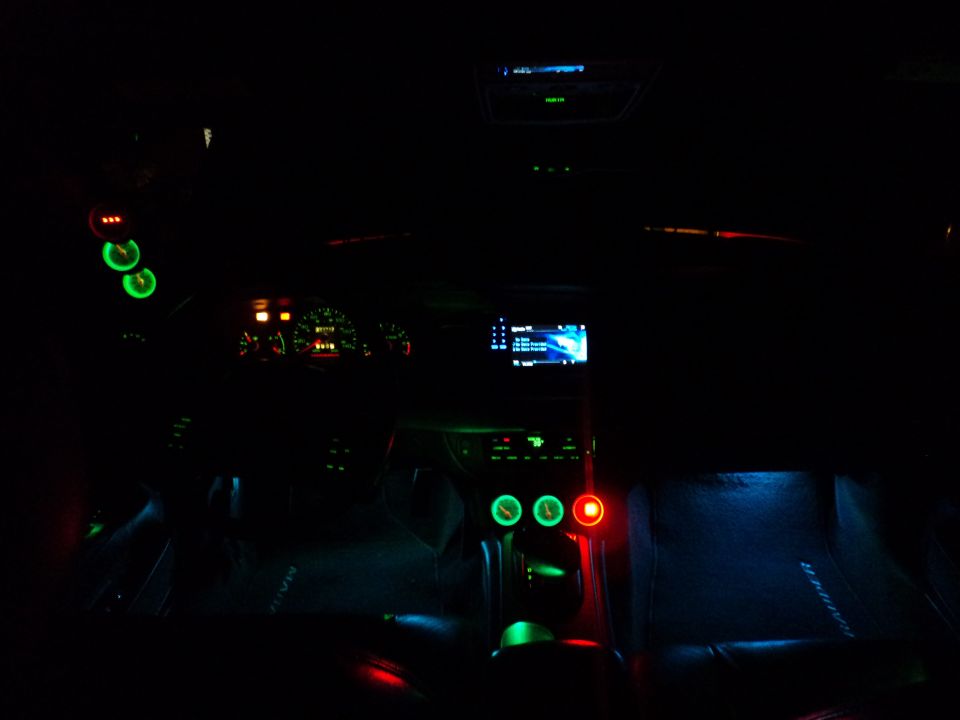 2004 Mercury Grand Marquis interior at night, showing dashboard gauges, aftermarket stereo, and custom green and blue interior lighting