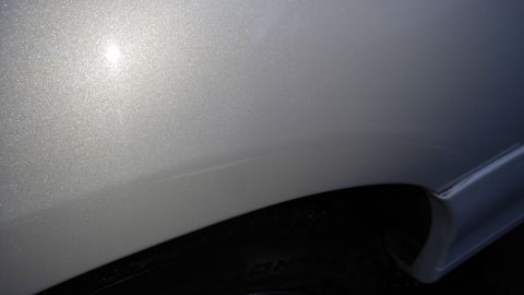 2004 Lincoln Town Car - Faint scratch visible on the fender of a silver car, near the wheel well.