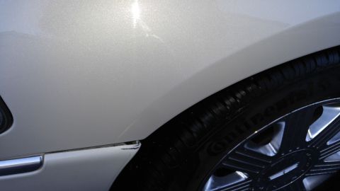2004 Lincoln Town Car - A close-up shot of the rear wheel well of a silver sedan, showing the tire and part of the body panel.