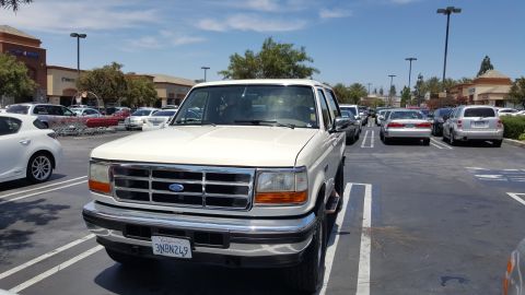 1995 Ford Bronco - A white 1995 Ford Bronco is seen parked in a shopping center lot on a sunny day.