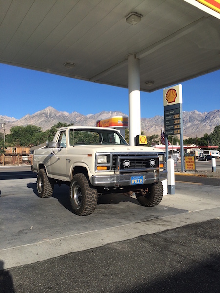 1981 Ford Bronco - This Ford pickup truck is parked at a gas station under a clear blue sky with mountains visible.