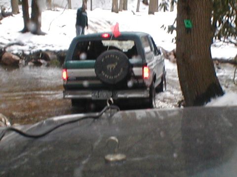 1979 Ford Bronco II - Rear view of a green and silver SUV navigating a snowy, wooded area.