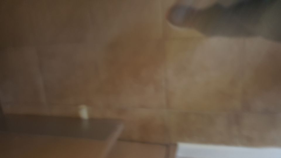 Close-up of wood-grain interior paneling with a small white object and a blurry hand