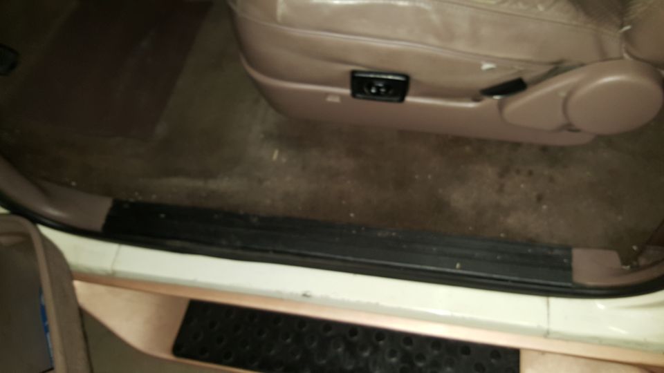 Open door view of tan power seat, dark carpet, black door sill and studded step pad