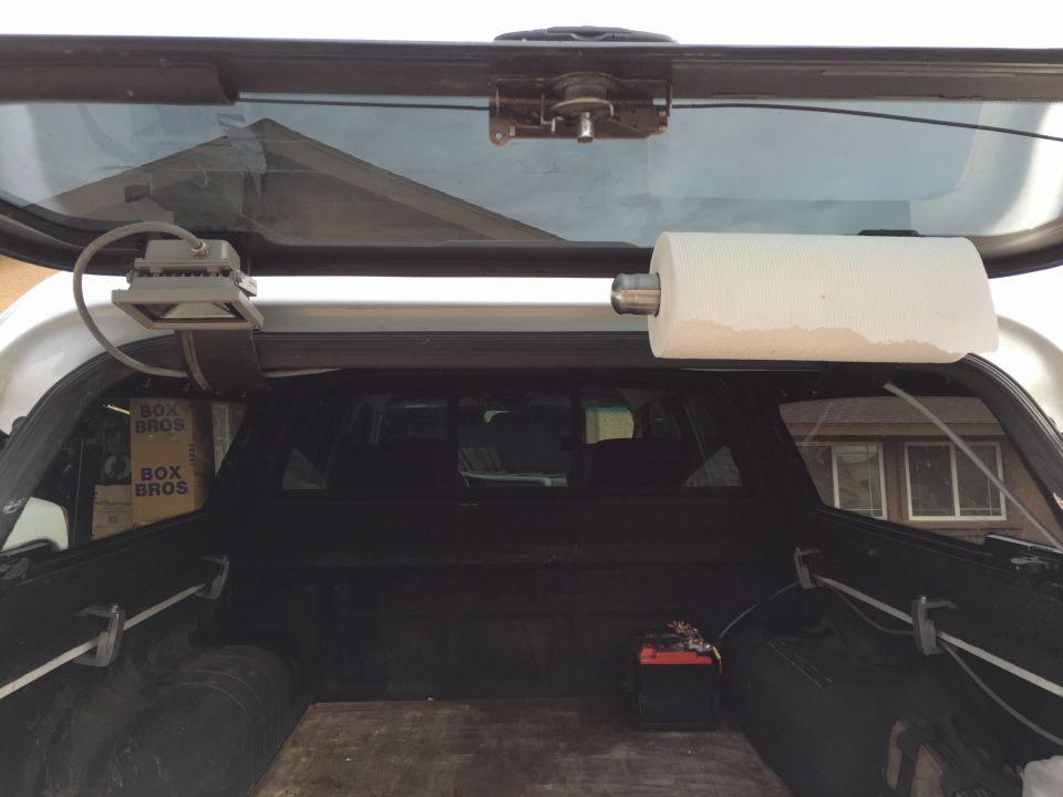 Truck bed interior with paper towel dispenser and battery. Boxes labeled 'BOX BROS' are visible