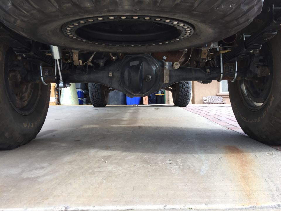 Underside view of a truck's rear axle, leaf springs, and spare tire mounted above