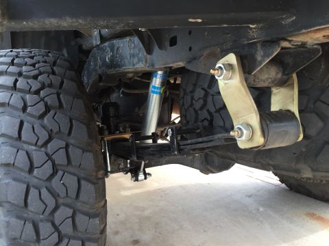 2001 Toyota Tacoma - The rear suspension system of a vehicle, leaf springs and a shock absorber, is shown with a large tire.