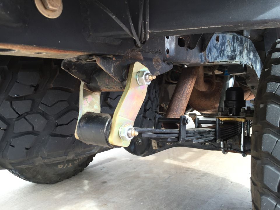 Truck leaf spring suspension with yellow bracket and black bushing near tire