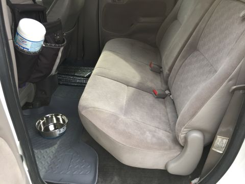 2001 Toyota Tacoma - The interior of a truck shows the rear seats, floor mats, a dog bowl, and a container of wipes in a seat organizer.