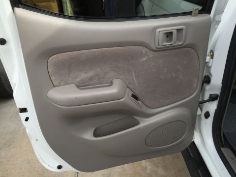 2001 Toyota Tacoma - Interior view of a white 2001 Toyota Tacoma's door panel, showing grey fabric and a speaker.