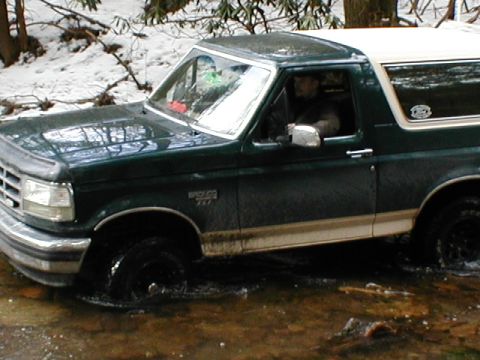 1979 Ford Bronco II - This Ford Bronco is navigating a wet, wooded area with snow on the ground.
