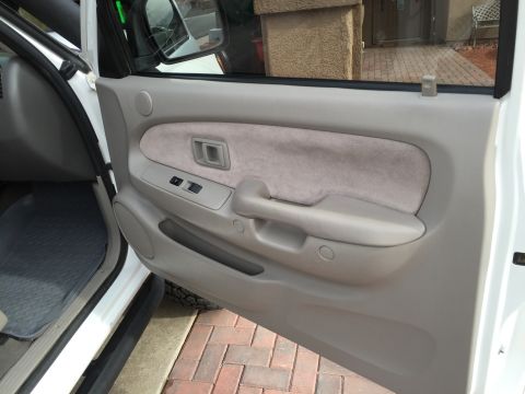 2001 Toyota Tacoma - The interior door panel of a 2001 Toyota Tacoma features power window controls and a fabric insert.
