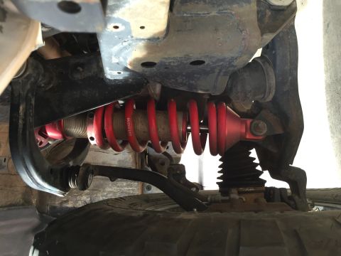 2001 Toyota Tacoma - Close-up of a vehicle's suspension system, showing a red coilover shock absorber and related parts.