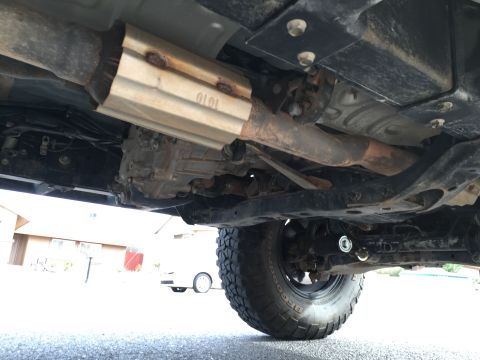 2001 Toyota Tacoma - The underside of a truck reveals its exhaust system, transmission, and a tire, with a white vehicle visible in the background.