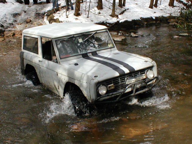 White SUV with black racing stripes driving through water