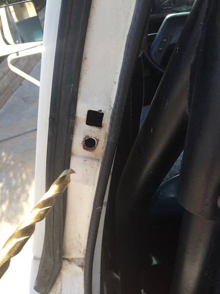1981 Ford Bronco - Close-up of a vehicle's door jamb shows rust and a drill bit, indicating repair work.