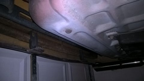 2004 Ford Crown Victoria - Underside view of a vehicle, showing the exhaust and part of the fuel tank. Garage door visible below.