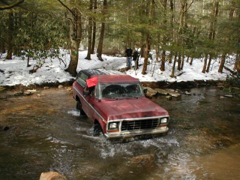1979 Ford Bronco II - This red Ford Bronco is navigating a stream in a snowy, wooded environment.