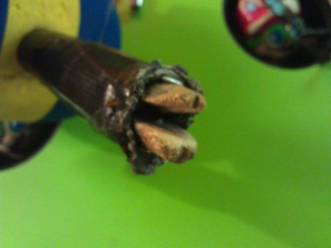 2006 Honda RANCHER - Close-up of a damaged wooden joystick, revealing frayed wires and a metallic casing, against a bright green background.