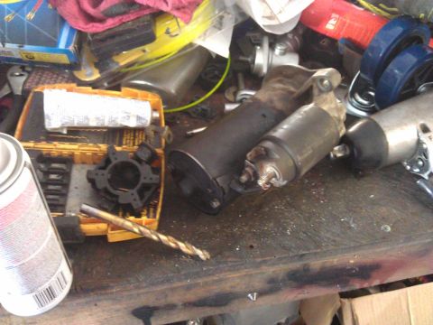 1994 Ford Bronco - Two automotive starters and a drill bit are visible on a workbench alongside various tools and parts.