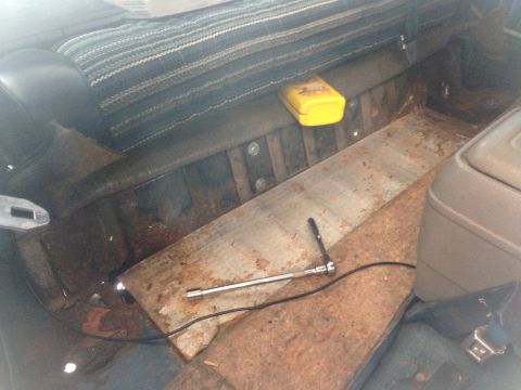 1979 Ford Bronco - The interior of an older vehicle shows a socket wrench and a yellow storage box on the floor.