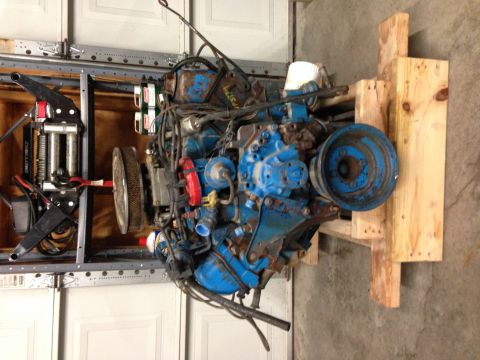 1979 Ford Bronco - A blue Ford V8 engine is mounted on a wooden stand, ready for work or transport.