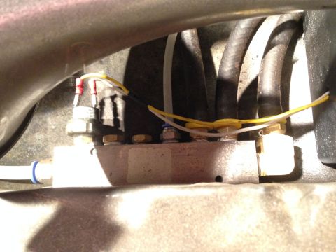1979 Ford Bronco - Detail of a vehicle's air suspension system, showing a valve block with multiple hoses and electrical connections.