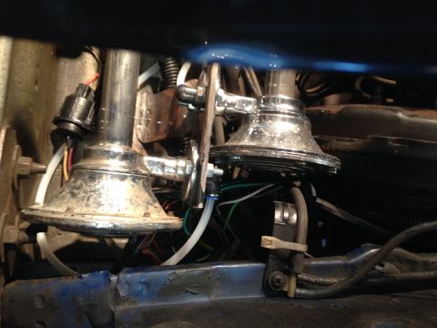 1979 Ford Bronco - Close-up view of chrome air horns, likely an aftermarket addition, with associated wiring and tubing.