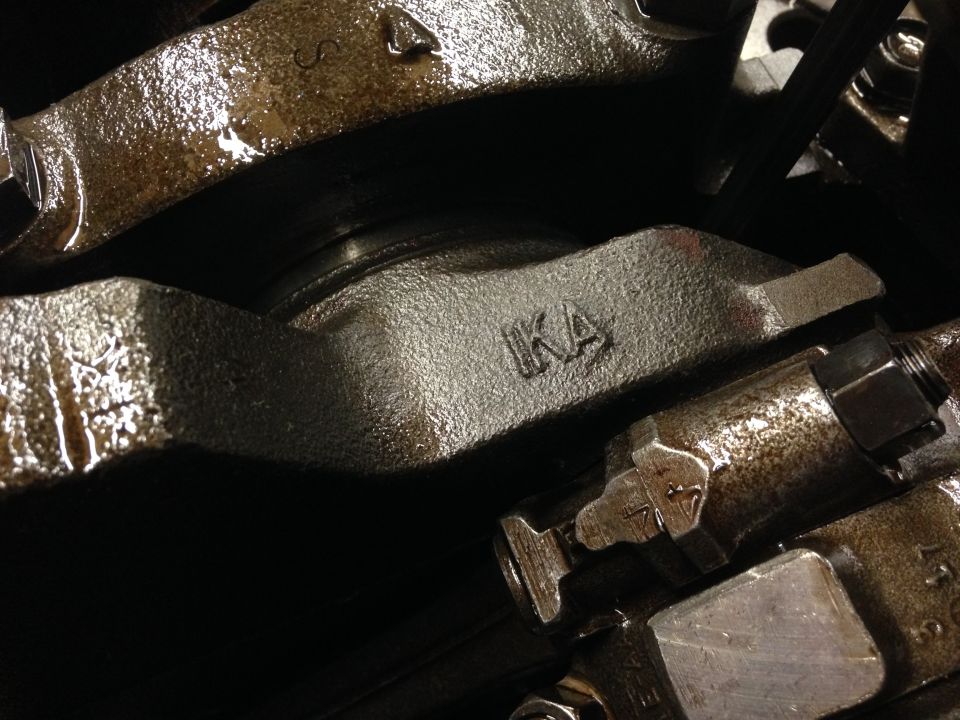 Close-up of engine crankshaft with connecting rod and some stamped markings like IKA
