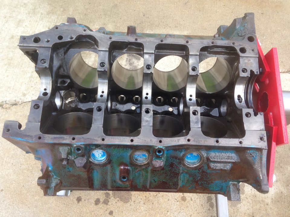 Engine block with four cylinders visible, showing internal components and some blue plugs