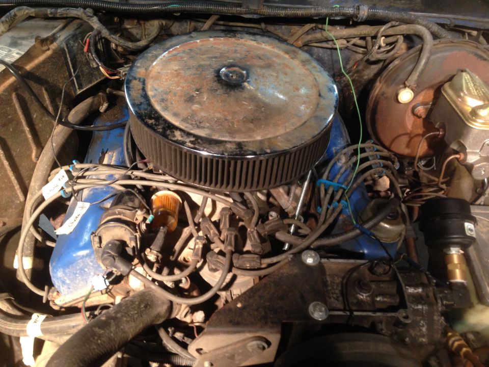 Engine bay with a large, rusty air cleaner, blue valve covers, and visible wiring
