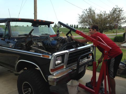1979 Ford Bronco - Man uses engine hoist to remove the engine from a black 1979 Ford Bronco.