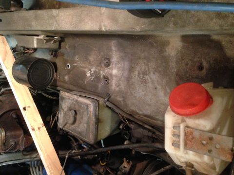 1979 Ford Bronco - Close-up view of engine bay components, including a reservoir and wiring, with a wooden support.