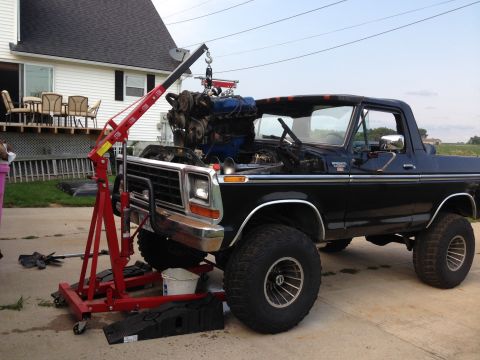 1979 Ford Bronco - A black 1978 Ford Bronco is having its engine removed by a red engine hoist.