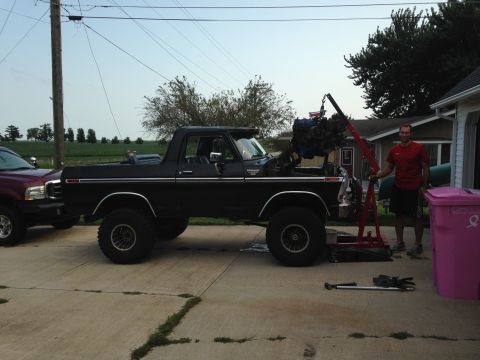 1979 Ford Bronco - Black Ford Bronco undergoing engine removal with an engine hoist. A second vehicle is parked nearby.