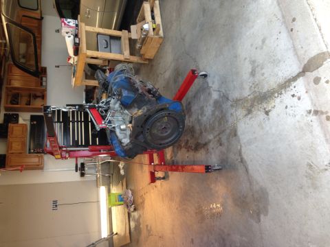 1979 Ford Bronco - An engine is mounted on a red engine stand, ready for work or rebuild in a garage setting.