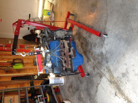 1979 Ford Bronco - Engine assembly being supported by a red engine hoist in a garage setting.